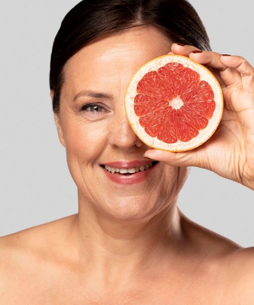 smiley-woman-holding-half-grapefruit-face-with-copy-space